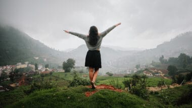 girl standing with arms raised wide surrounded by hills ooty itinerary