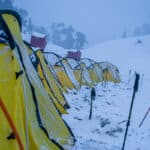 yellow tents surrounded with white snow winter trek