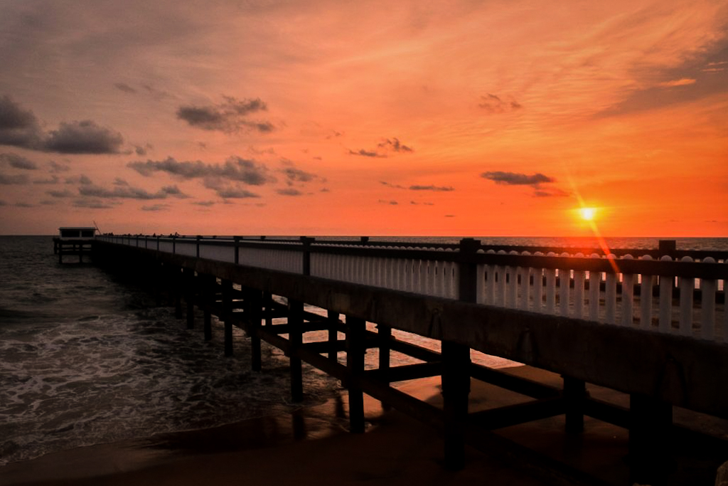 sun setting behind a pier
