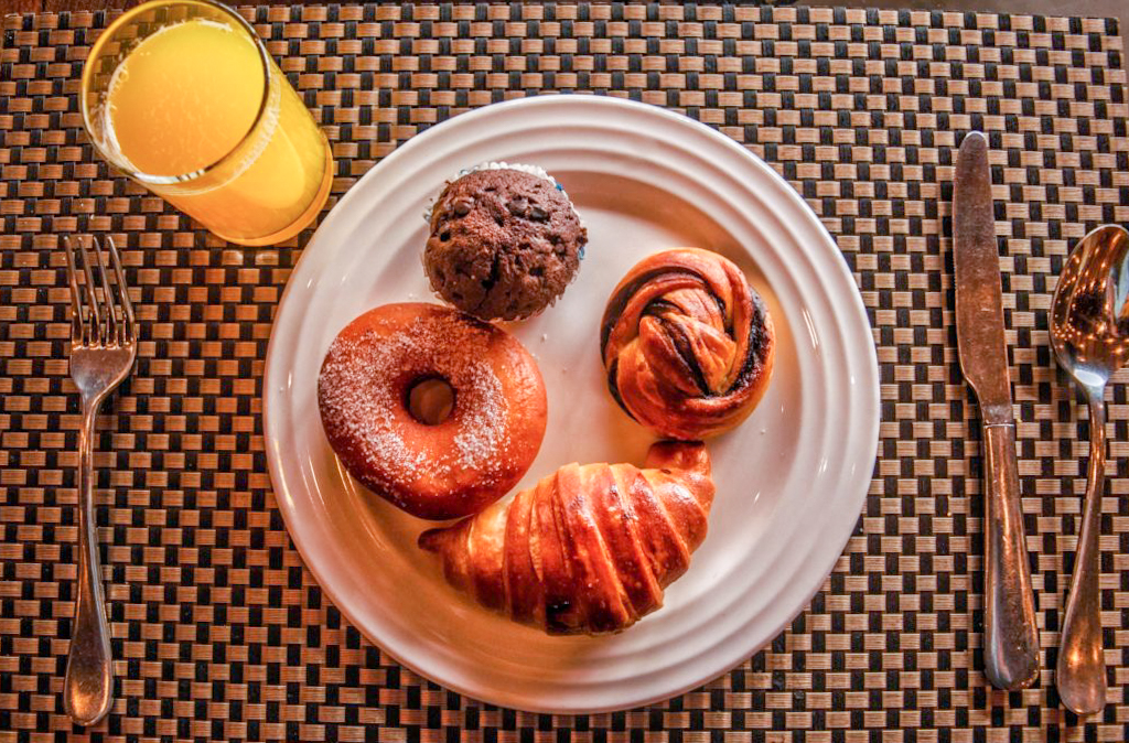 Donuts and croissant on a plate with a glass of juice aahana resort ramnagar