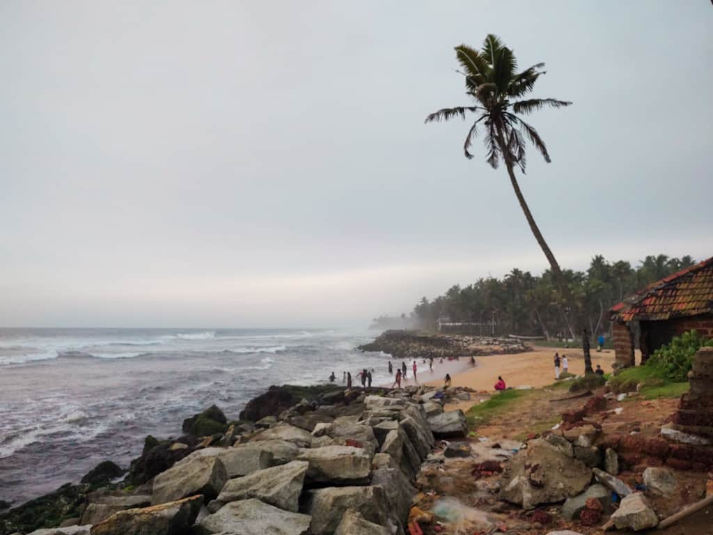 Beach with people surrounded by trees and stones