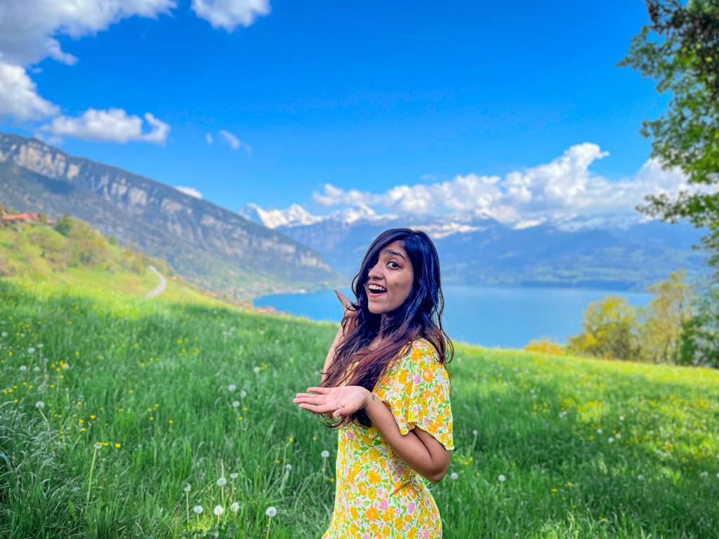 girl in front of a lake, mountains, and lush greenery