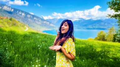 girl standing in front of a green field and blue lake apply for schengen visa