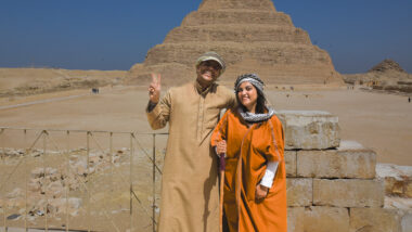 woman in orange standing with a man in front of a pyramid